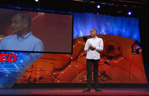 Pico Lyer speaking on a stage at Ted Talk