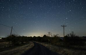 road at night with a view of the dark sky with stars