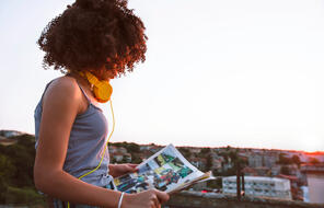 Portrait of a teenage girl on a rooftop, reading a comic and enjoying the sunset.