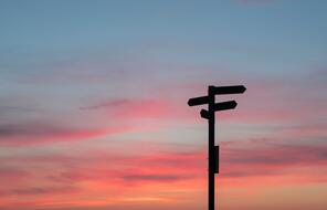 Street signs with the sunset behind it