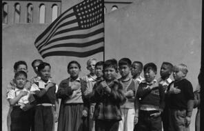 Several children from families of Japanese ancestry stand with their hand over their heart reciting the Pledge of Allegiance in San Francisco, California in 1942.