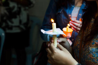 Closeup of people holding candle vigil in darkness expressing and seeking hope