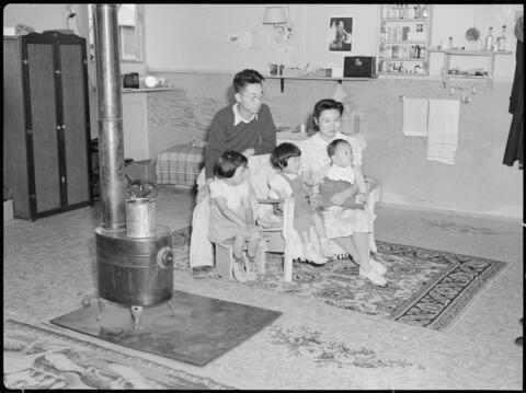 Tule Lake Relocation Center, Newell, California. An evacuee family spends a quiet evening in their barracks. The decoration of this apartment is quite typical and shows the homemade furniture, shelves, bookcases and other furniture.