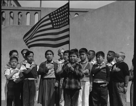 Several children from families of Japanese ancestry stand with their hand over their heart reciting the Pledge of Allegiance in San Francisco, California in 1942.